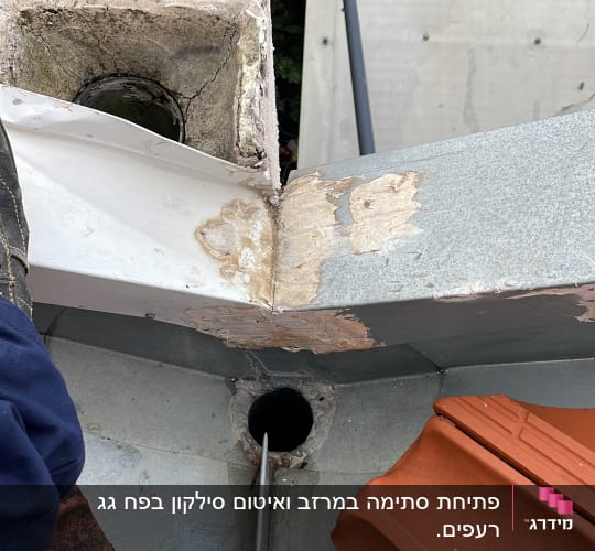 צינור מתכת נכנס לפתח ניקוז בגג
